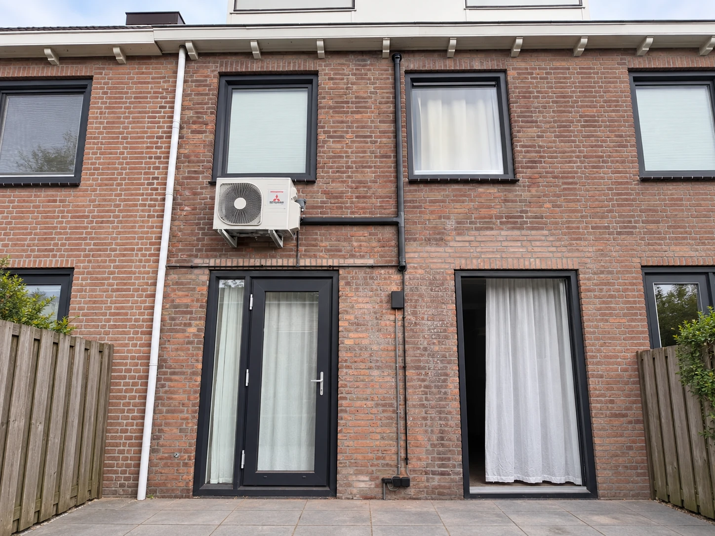 Buitenunit op muurbeugels aan een bakstenen achtergevel